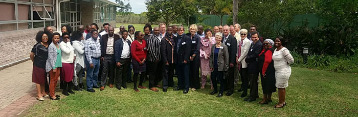 Large group of people standing in a garden in a curved row about three deep