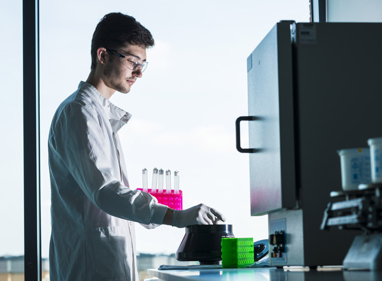 A student in a lab coat using the superlab facilities.