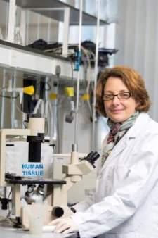 Female in a lab next to a microscope