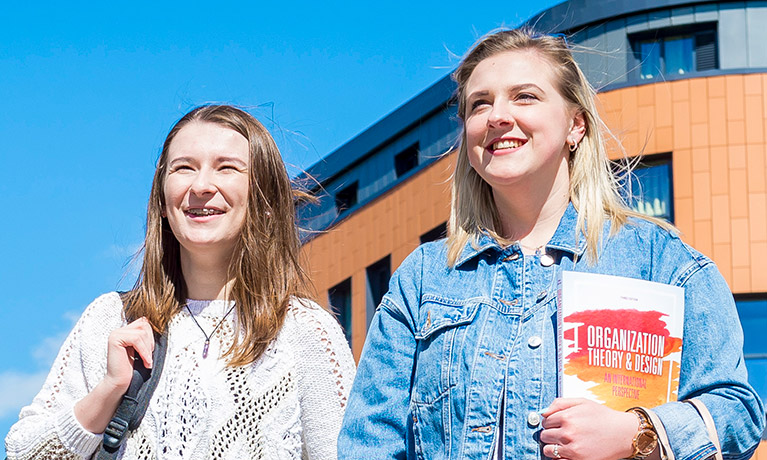 Two females outside accommodation on a sunny day