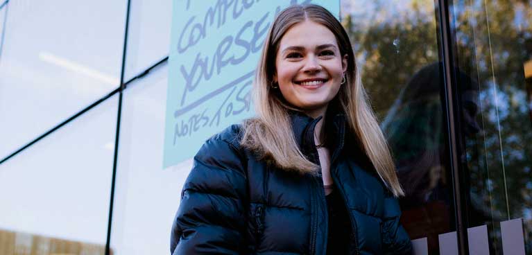 A female student standing in front of campus building