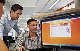 Couple of male students in smart shirts looking at laptop 