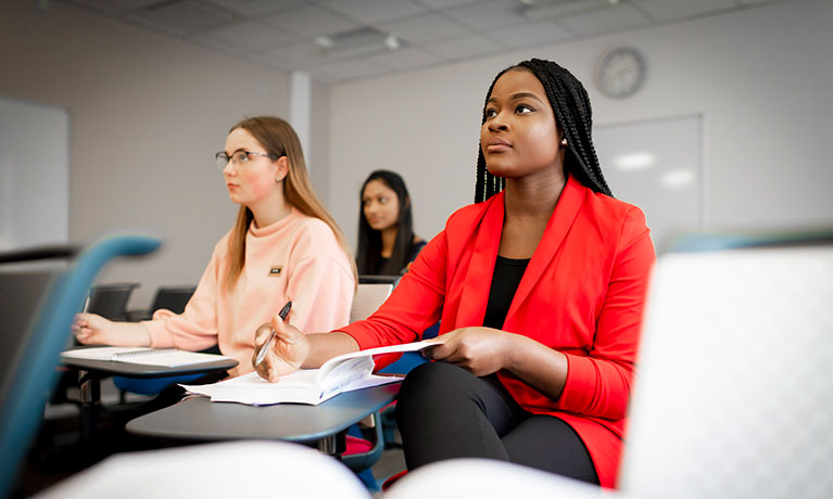 Three female students sat in a classroom looking to the front