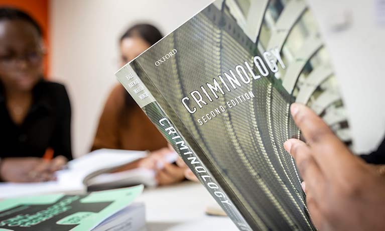 close up of hands holding a criminology textbook  