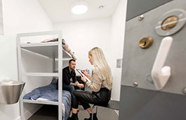 Student interviewing an acting criminal in a mock cell 