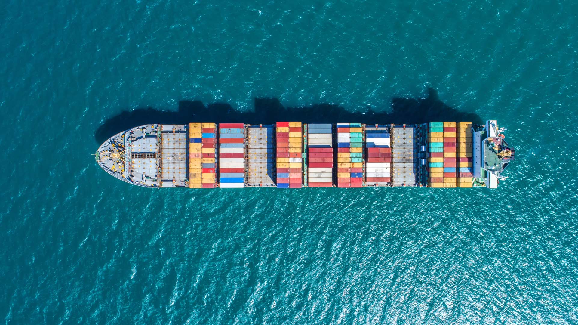 Container ship loaded up with colourful containers, water either side