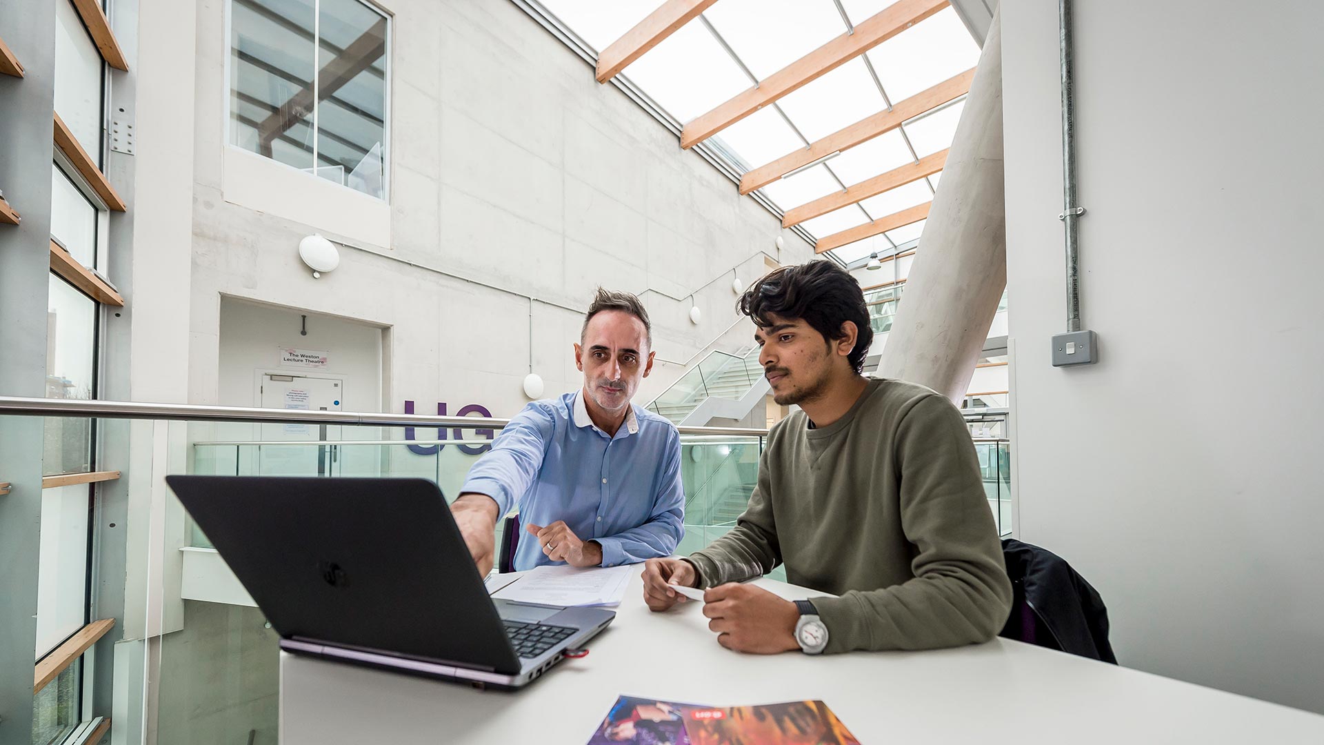 Two males working on a digital product in a grey building