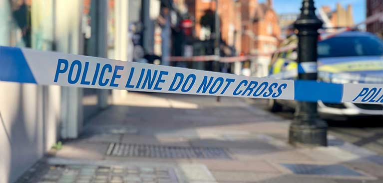 Street with tape across saying, police line do not cross