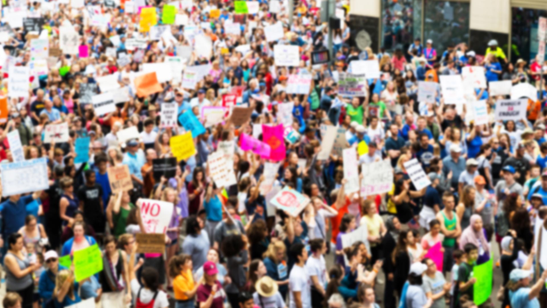 Aerial view of a crowd marching holding placards.