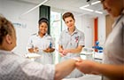 Students in a mock hospital ward help a patient