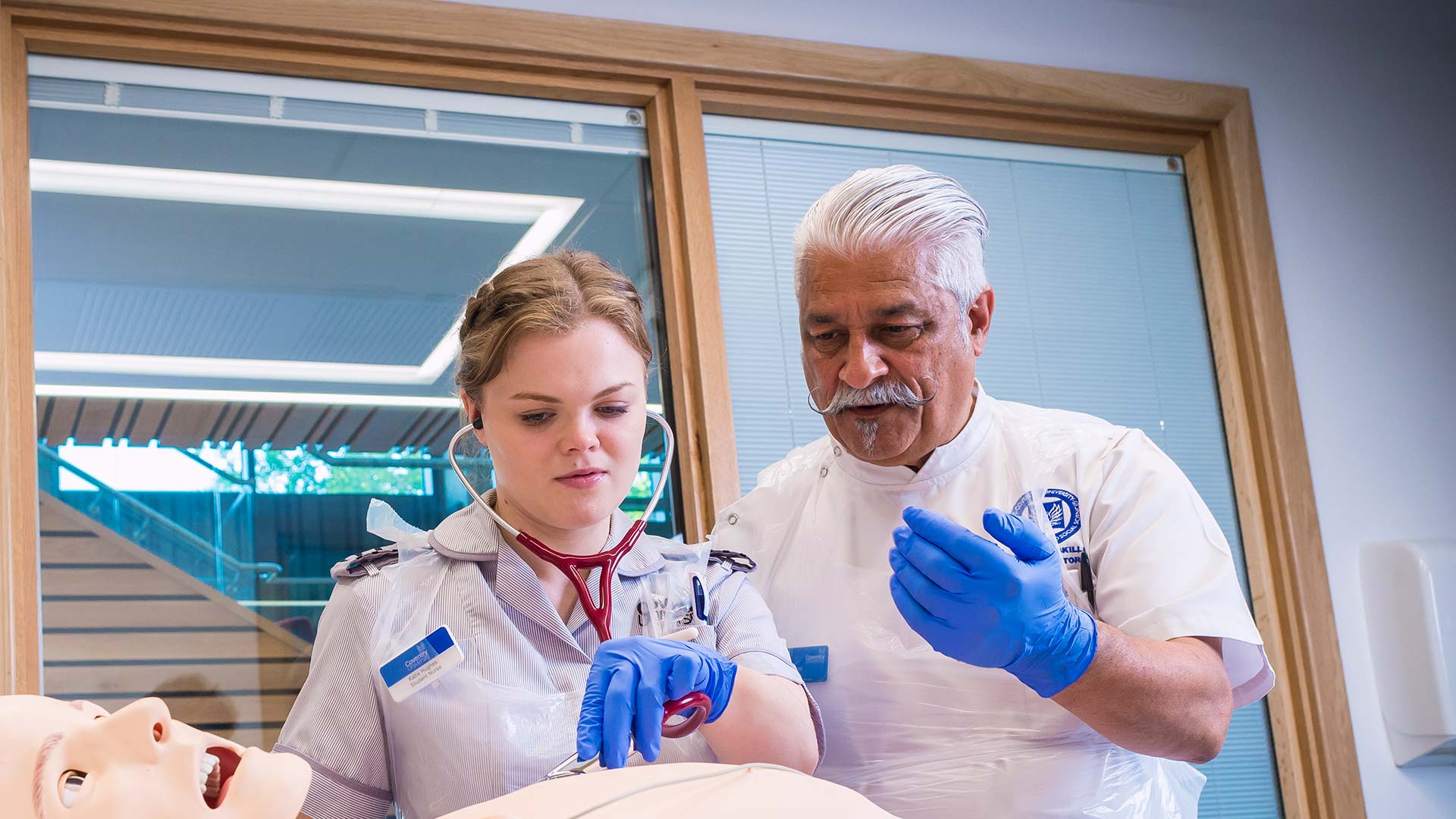 A tutor instructing a student using a manikin