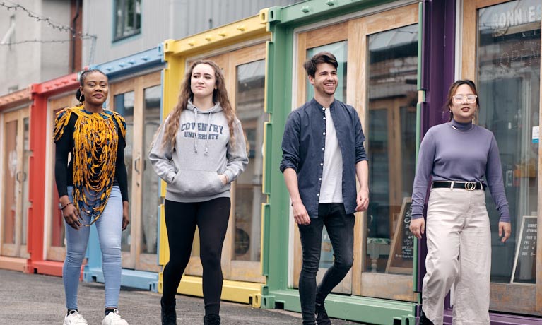 Four students walking along some shop fronts in Fargo village