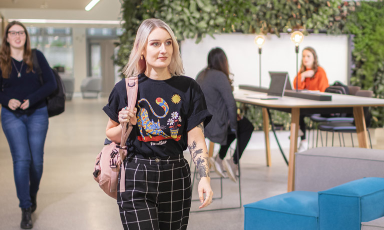 Blonde hair female student walking in the Student hub