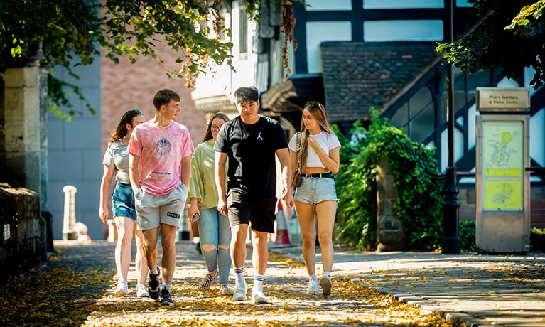 Group of young adults walking down a narrow street near an old building