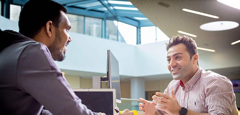 smiling tutor engaged in conversation with male student