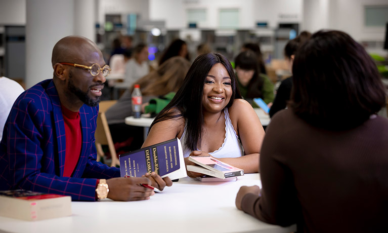 3 students in discussion sitting at a table 