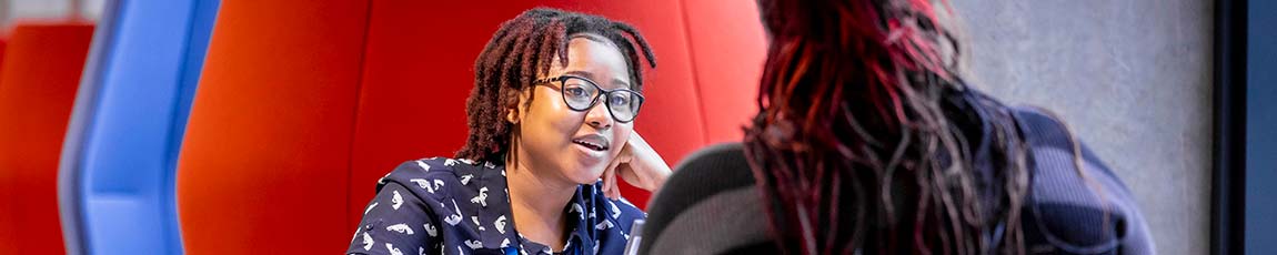 Female student sat opposite another student talking