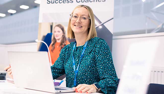 Female success coach sitting at a desk with an open laptop