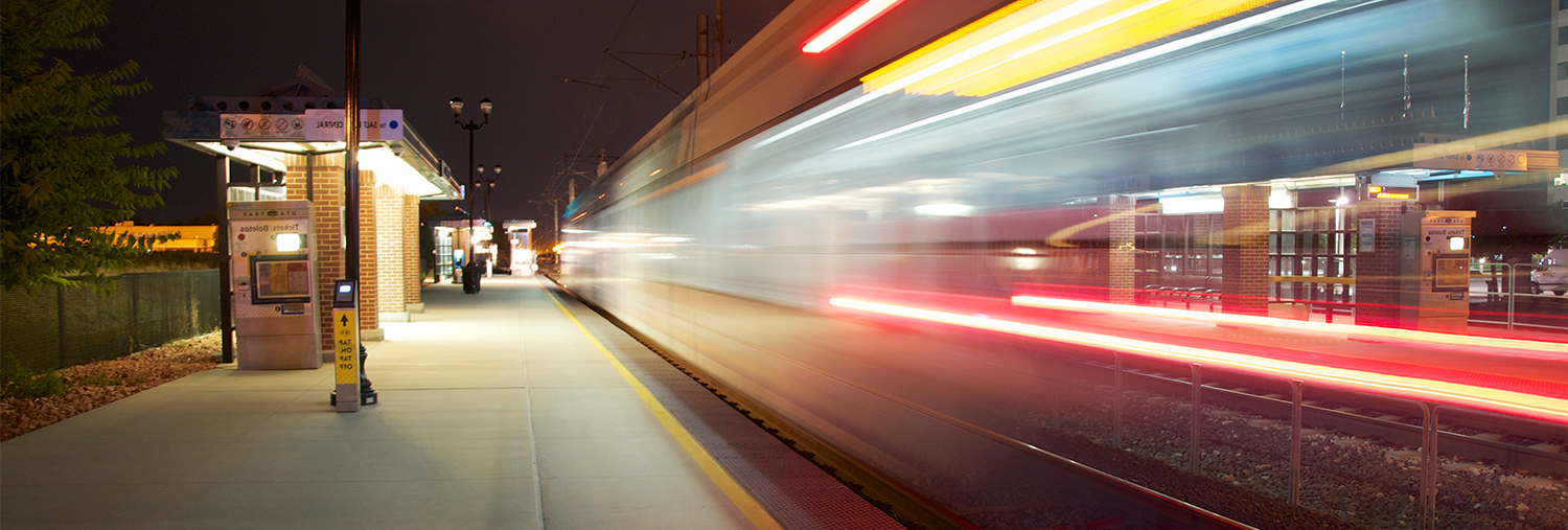 Blurred training moving fast through train station at night.