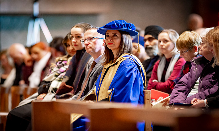 Lady sitting with blue graduation cap and gown on