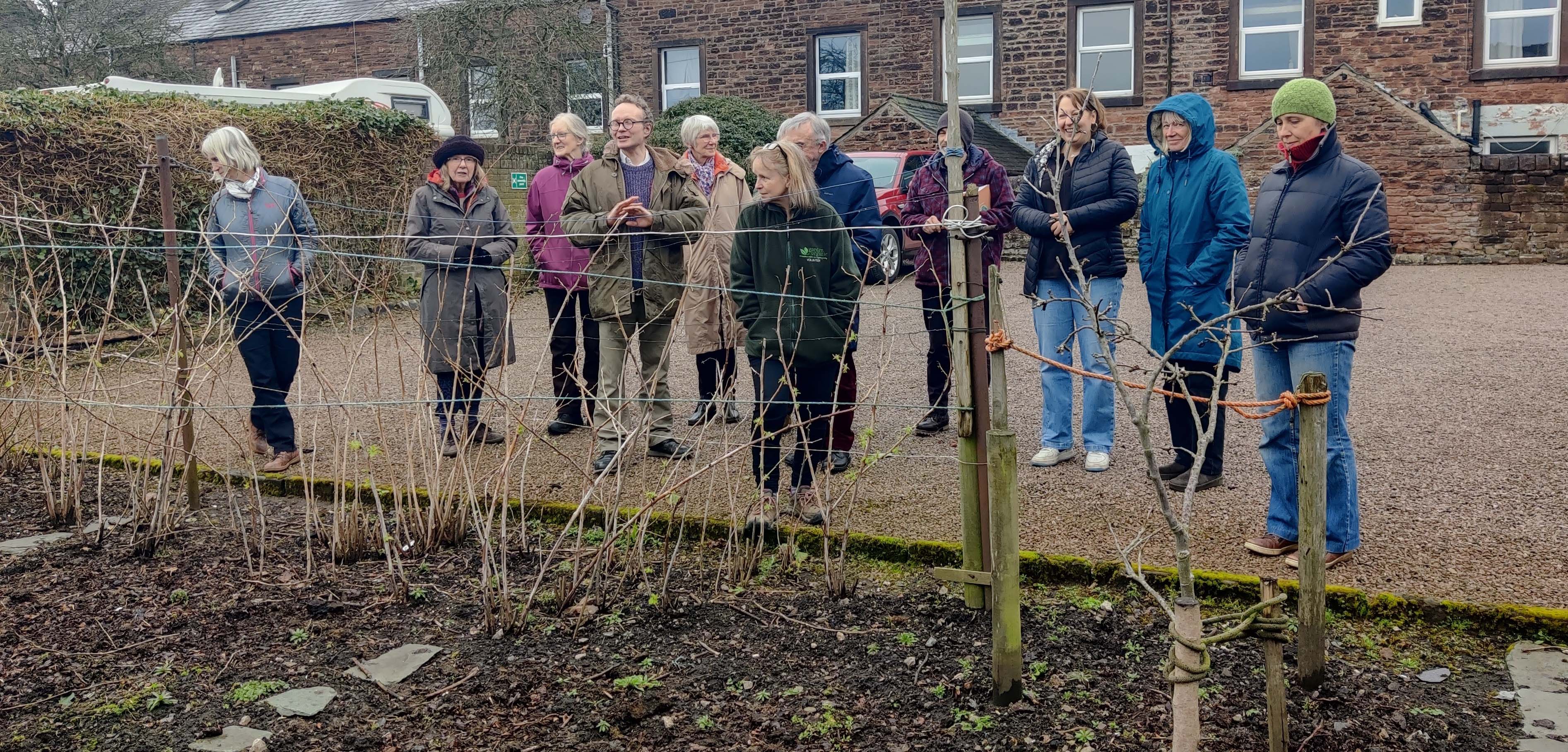 A group of people observing plastic use on an allotment