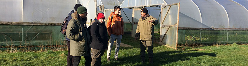 A group of people stood outside two polytunnels.