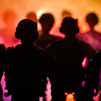 Silhouette of police in riot gear against an orange sky