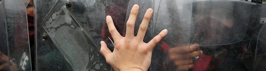 Hand pushing against police riot shields