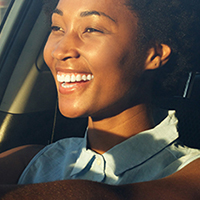 A smiling woman driving a car