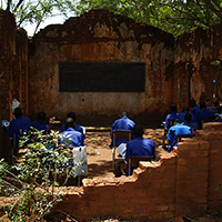 People working at desks in a bombed out school in sudan