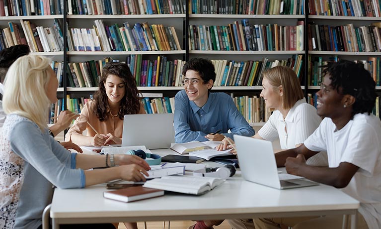 Students sat around desk in library.