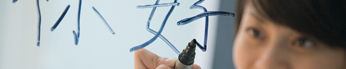 Chinese woman writing 'hello' in Chinese on a clear screen.