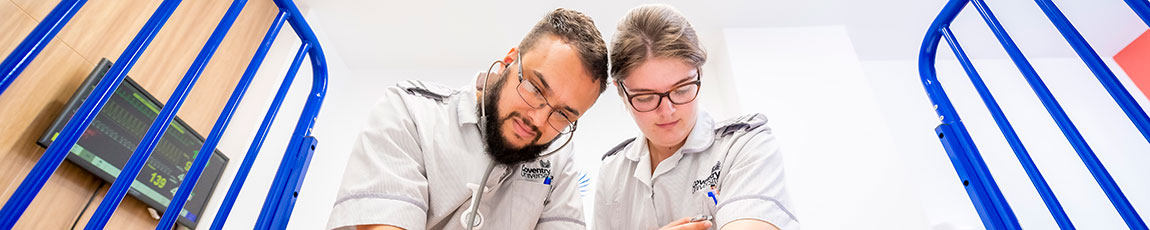 male and female student nurses lookin over a hospital bed