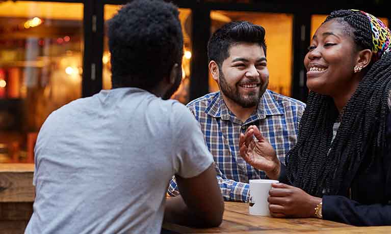 Three students sat at a table talking