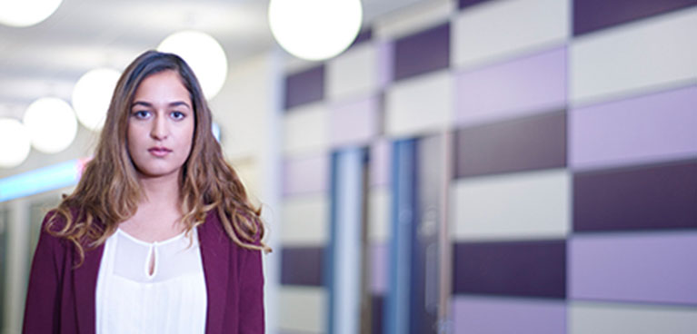 Concerned woman stands to left of image with long corridor behind her