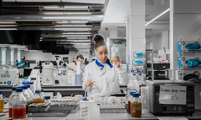 Female student in a laboratory setting checking a test tube