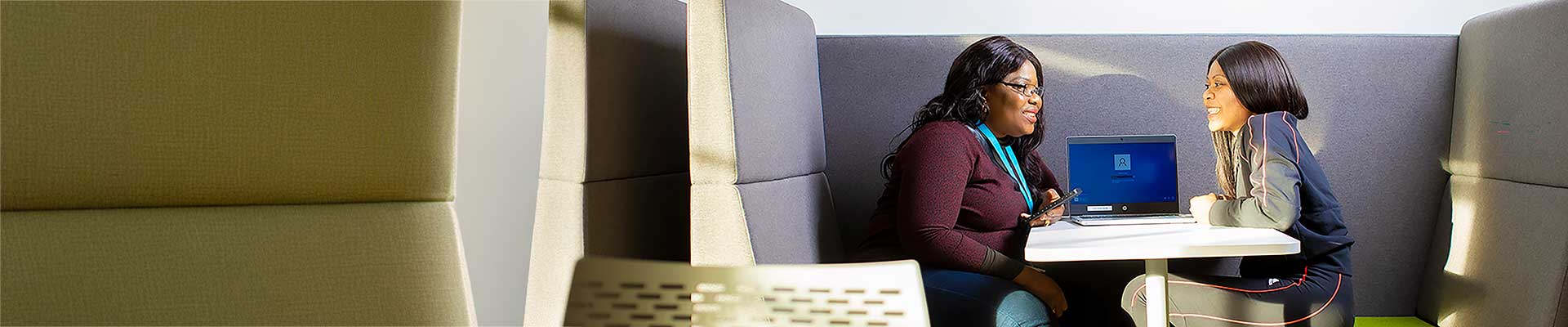 Two students sat at a desk talking to each other