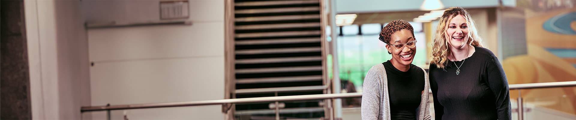 Two students laughing whilst walking indoors