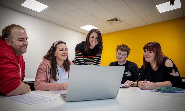 Group of students working together looking at one laptop