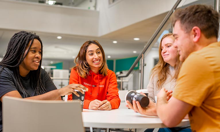 Group of students sat at a table socialising