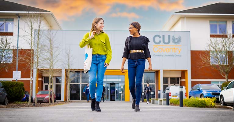 Two students talking outside walking away from the CU Coventry building