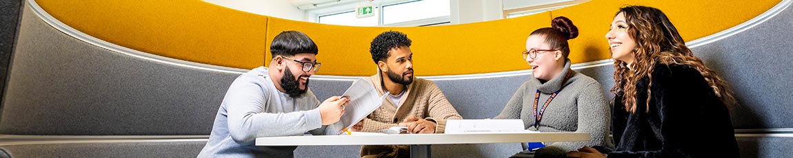 Four students sat in a pod talking in a CU Coventry building