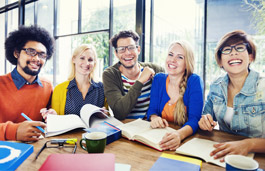 A group of professionals with notebooks and papers on the table in front of them, smiling at the camera.