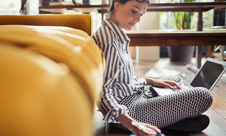 Female sitting down with legs crossed and looking at a laptop