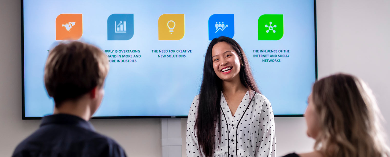 Woman presenting to students infront of digital whiteboard